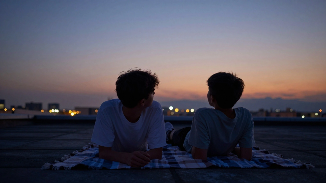 A sibling pair stargazing on a rooftop at dusk, blanket beneath them.