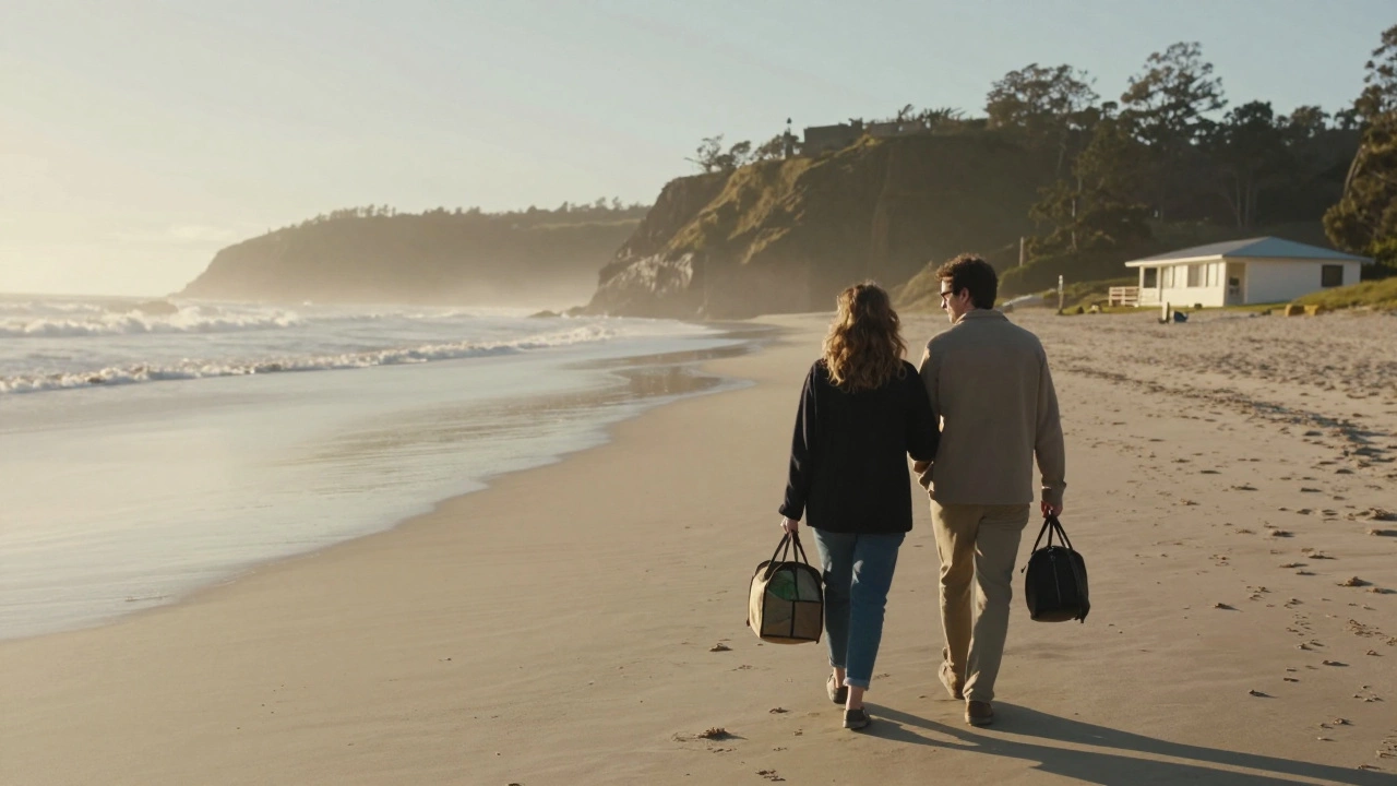 Couple walking a quiet coastal beach at sunrise, holding coffee and packed lunch, modest motel in the background.